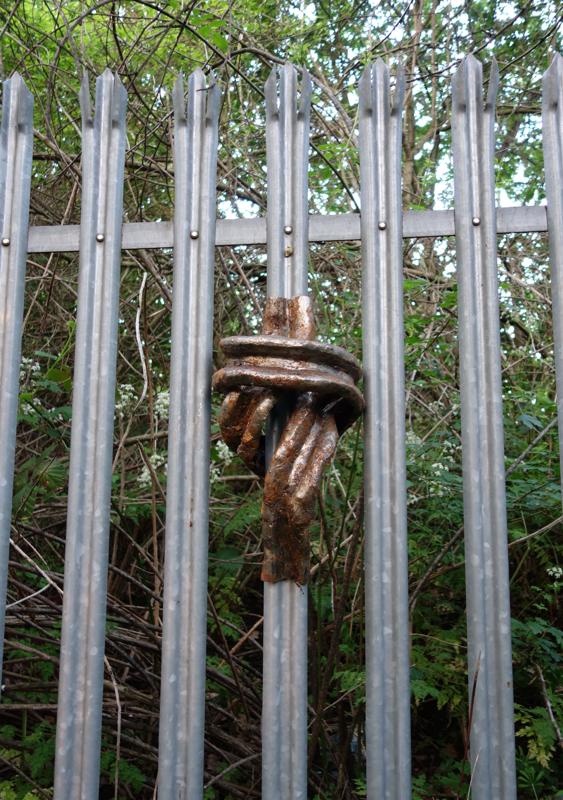 Steel sculpture meant to mimic the shape of a palisade fence that has been bent into a knot